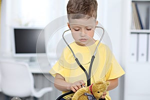 Doctor and patient in hospital. Happy little boy having fun while being examined with stethoscope. Healthcare and