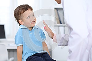 Doctor and patient in hospital. Happy little boy having fun while being examined with stethoscope. Healthcare and