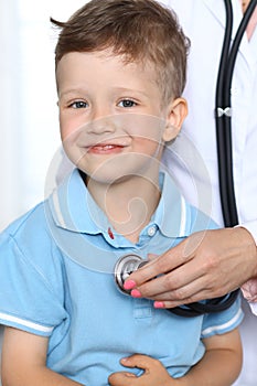 Doctor and patient in hospital. Happy little boy having fun while being examined with stethoscope. Healthcare and