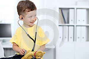 Doctor and patient in hospital. Happy little boy having fun while being examined with stethoscope. Healthcare and