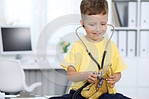 Doctor and patient in hospital. Happy little boy having fun while being examined with stethoscope. Healthcare and