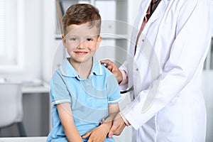 Doctor and patient in hospital. Happy little boy having fun while being examined with stethoscope. Healthcare and