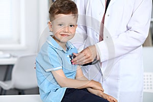 Doctor and patient in hospital. Happy little boy having fun while being examined with stethoscope. Healthcare and