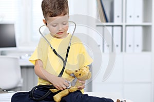 Doctor and patient in hospital. Happy little boy having fun while being examined with stethoscope. Healthcare and