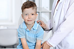 Doctor and patient in hospital. Happy little boy having fun while being examined with stethoscope. Healthcare and