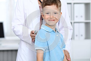 Doctor and patient in hospital. Happy little boy having fun while being examined with stethoscope. Healthcare and