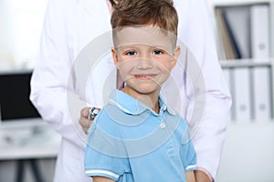 Doctor and patient in hospital. Happy little boy having fun while being examined with stethoscope. Healthcare and