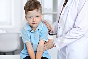 Doctor and patient in hospital. Happy little boy having fun while being examined with stethoscope. Healthcare and