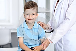 Doctor and patient in hospital. Happy little boy having fun while being examined with stethoscope. Healthcare and