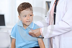 Doctor and patient in hospital. Happy little boy having fun while being examined with stethoscope. Healthcare and