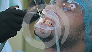 Doctor and patient with lip dilator in the dental office, close up of cleaning and rinsing of the teeth