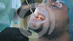 Doctor and patient with lip dilator in the dental office, close up of cleaning and rinsing of the teeth, final