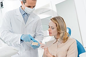 Doctor and patient looking at jaws model in modern