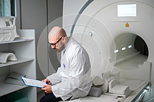 Doctor with a patient medical card near MRI scanner in a hospital