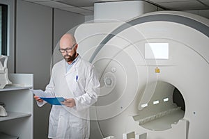 Doctor with a patient medical card near MRI scanner in a hospital