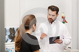 Doctor and patient in medical office. Therapist talking to patient in office, taking notes, writing prescription