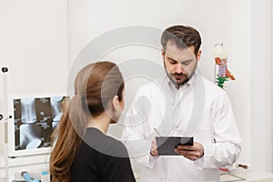 Doctor and patient in medical office. Therapist talking to patient in office, taking notes, writing prescription