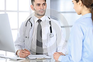 Doctor and patient. Physician man filling up medication history records form while sitting at the glass desk in medical