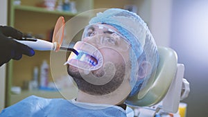 Doctor and patient with retractor in the dental office, cleaning with ultraviolet light and orange protective screen