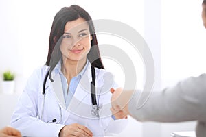 Doctor and patient shaking hands to each other. Healthcare, medicine and trusting concept