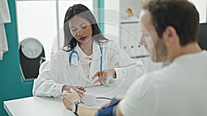 Doctor and patient sitting on table measuring pulse using tensiometer at the clinic