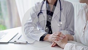 Doctor and patient sitting at the table and talking. The pediatrician in a blue dotted blouse and white medical coat is