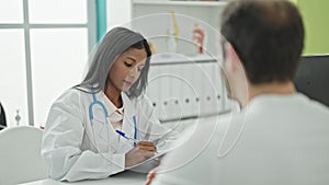 Doctor and patient sitting on table writing medical report at the clinic
