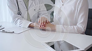 Doctor and patient sitting at the white table in the hospital. The pediatrician in a green blouse and white medical coat