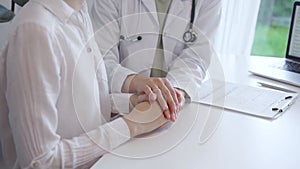 Doctor and patient sitting at the white table in the hospital. The pediatrician in a green blouse and white medical coat