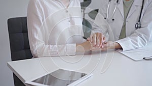 Doctor and patient sitting at the white table in the hospital. The pediatrician in a green blouse and white medical coat