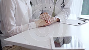 Doctor and patient sitting at the white table in the hospital. The pediatrician in a green blouse and white medical coat