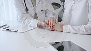 Doctor and patient sitting at the white table in the hospital. The pediatrician in a green blouse and white medical coat