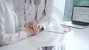 Doctor and patient sitting at the white table in the hospital. The pediatrician in a green blouse and white medical coat