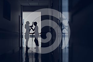 Doctor and patient with stick are standing in hallway