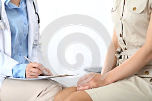 Doctor and patient talking. Physician at work in hospital while writing up medication history records form on clipboard