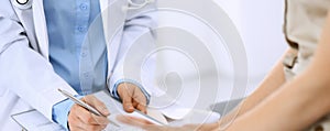 Doctor and patient talking. Physician at work in hospital while writing up medication history records form on clipboard