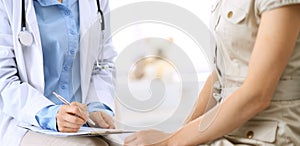Doctor and patient talking. Physician at work in hospital while writing up medication history records form on clipboard