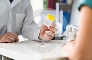 Doctor, patient and urine test cup. Physician giving pee container to a woman in clinic or hospital emergency room. photo