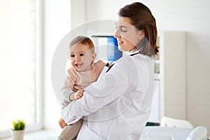 Doctor or pediatrician holding baby at clinic