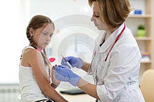 Doctor pediatrician holding syringe with injection vaccination. Girl is afraid.