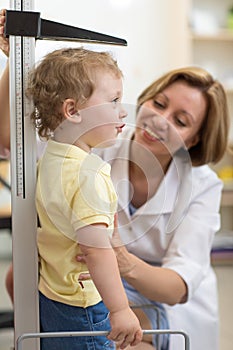 Doctor measures growth smiling child boy in medical office, profile