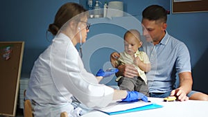 Doctor pediatrician writes a treatment plan in a medical record. Father and his little son examined by a doctor