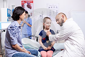 Doctor pediatry giving child checkup in medical office using stethoscope