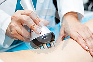 Doctor performing a radiofrequency treatment on a female patient leg photo