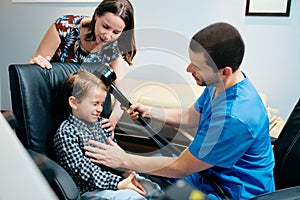 Paediatrician Doctor Doing Brain Treatment To Autistic Child In Clinic photo