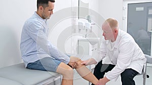 Doctor performs knee reflex test on male patient in a clinical setting