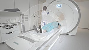The doctor performs an MRI scan for a patient at the clinic. The girl lies in the MRI device. Magnetic resonance imaging