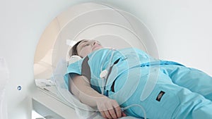 The doctor performs an MRI scan for a patient at the clinic. The girl lies in the MRI device. Magnetic resonance imaging