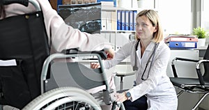 Doctor performs neurological examination of knee joint of woman in wheelchair