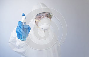 Doctor in personal protective equipment or PPE. holding alcohol spray bottle